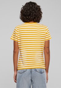 Yellow and white striped t-shirt with a crew neck and short sleeves, made from soft cotton fabric. Features a relaxed fit and straight hem.