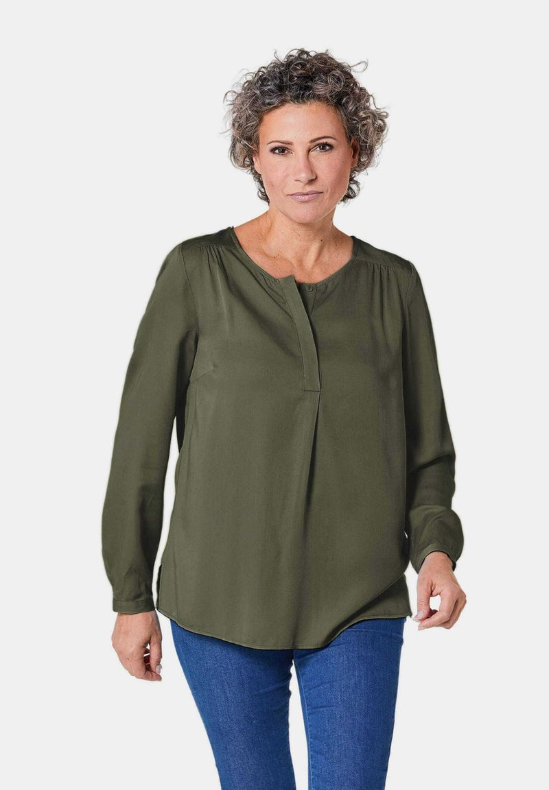 Olivgrüne Bluse mit langen Ärmeln, runder Ausschnitt und Knopfleiste vorne. Glattes Material mit lockerer Passform und abgerundetem Saum.