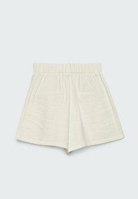 Shorts blancs taille haute avec une ceinture élastique, des passants pour ceinture, des plis à l'avant et des poches latérales sur un fond gris clair.