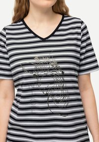 Czarna i biała koszulka w paski z dekoltem w serek, z graficznym nadrukiem w kolorze srebrnym na przodzie. Wykonana z miękkiego, lekkiego materiału.