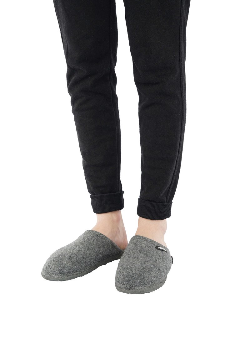 Gray felt slippers with open back, rounded toe, and rubber sole, paired with black tapered pants featuring ribbed cuffs.