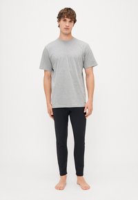 Šedé bavlněné tričko s krátkým rukávem v kombinaci s černými slim-fit kalhotami. Jednoduchý design, hladká textura a neutrální barvy.