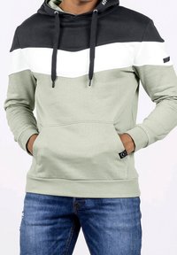 Felpa con cappuccio in verde chiaro, nero e bianco. Presenta un design a chevron, coulisse, una tasca frontale e polsini a coste.