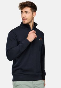 Sudadera de corte recto con cremallera hasta el pecho en mezcla de algodón, que presenta puños y dobladillo de canalé, con un sutil detalle del logo naranja en el pecho.