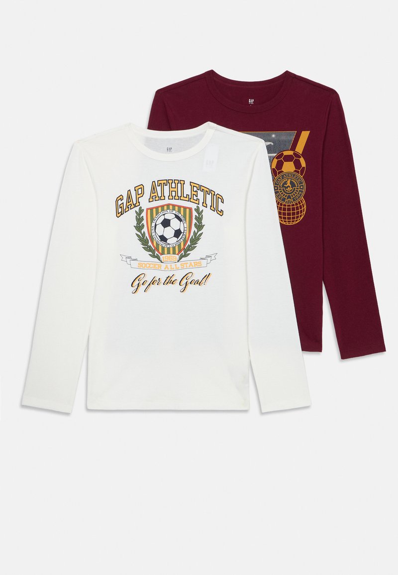 Zwei Langarmshirts mit Rundhalsausschnitt, eines in Weiß mit Fußballwappen und dem Text "GAP Athletic", das andere in Bordeauxrot mit einem Sportgrafikdesign, auf einem weißen Hintergrund flach ausgelegt.