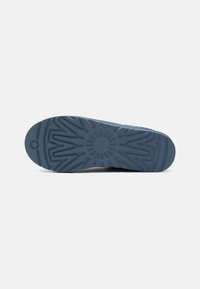 Blue rubber shoe sole featuring a textured tread with geometric patterns, a circular emblem in the center, and smooth edges.
