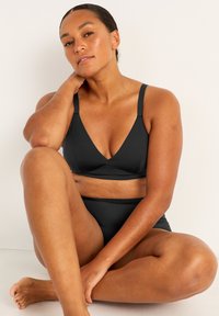Svart bikini-set som har en V-ringad topp med breda axelband och matchande högmidjade bottoms. Slät yta och minimal design.