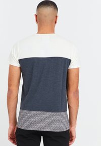 Multifarvet t-shirt med en cremet øverste del, mørkeblå midte og mønstret grå kant. Casual pasform med korte ærmer og rund hals.
