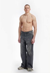 Grå denim jeans med løs passform, utstyrt med buede sømmer og middels midjehøyde. Komplementert med nøytralt tonede sneakers.