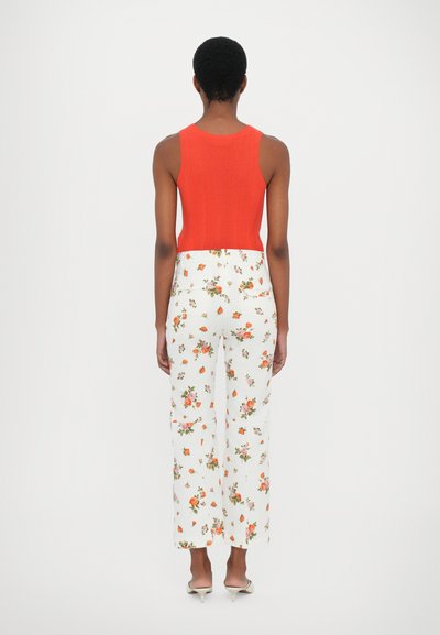 Red ribbed tank top paired with white floral print wide-leg trousers featuring orange and pink blooms, viewed from the back.