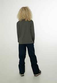 Langärmliges olivgrünes Hemd, Rückansicht, kombiniert mit locker sitzenden, navyblauen Hosen, die eine entspannte Silhouette und minimale Details aufweisen.