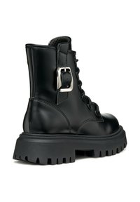 Des bottines noires à lacets présentent une tige en cuir brillant, une semelle en caoutchouc épaisse avec des motifs antidérapants, et un accent de boucle en métal argenté sur le côté.