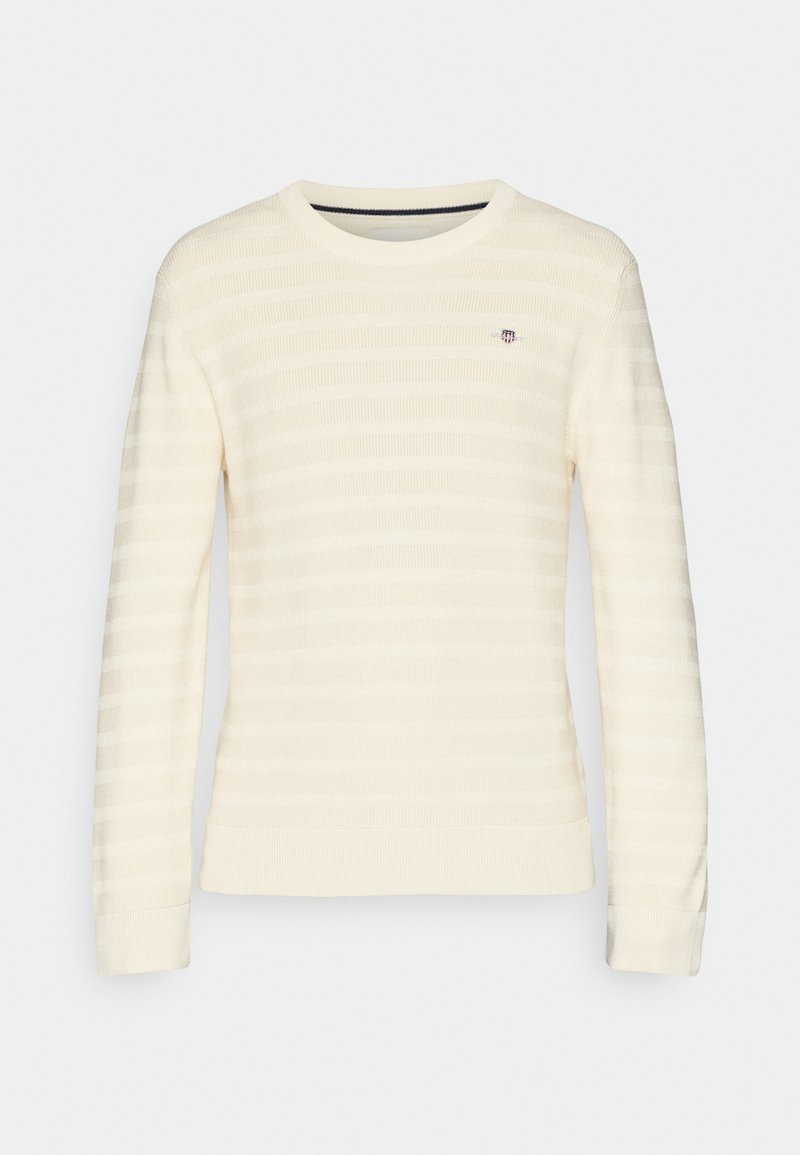 Jasna kremowa sweter w paski z długimi rękawami, okrągłym dekoltem, dzianinową fakturą i małym logo na piersi.