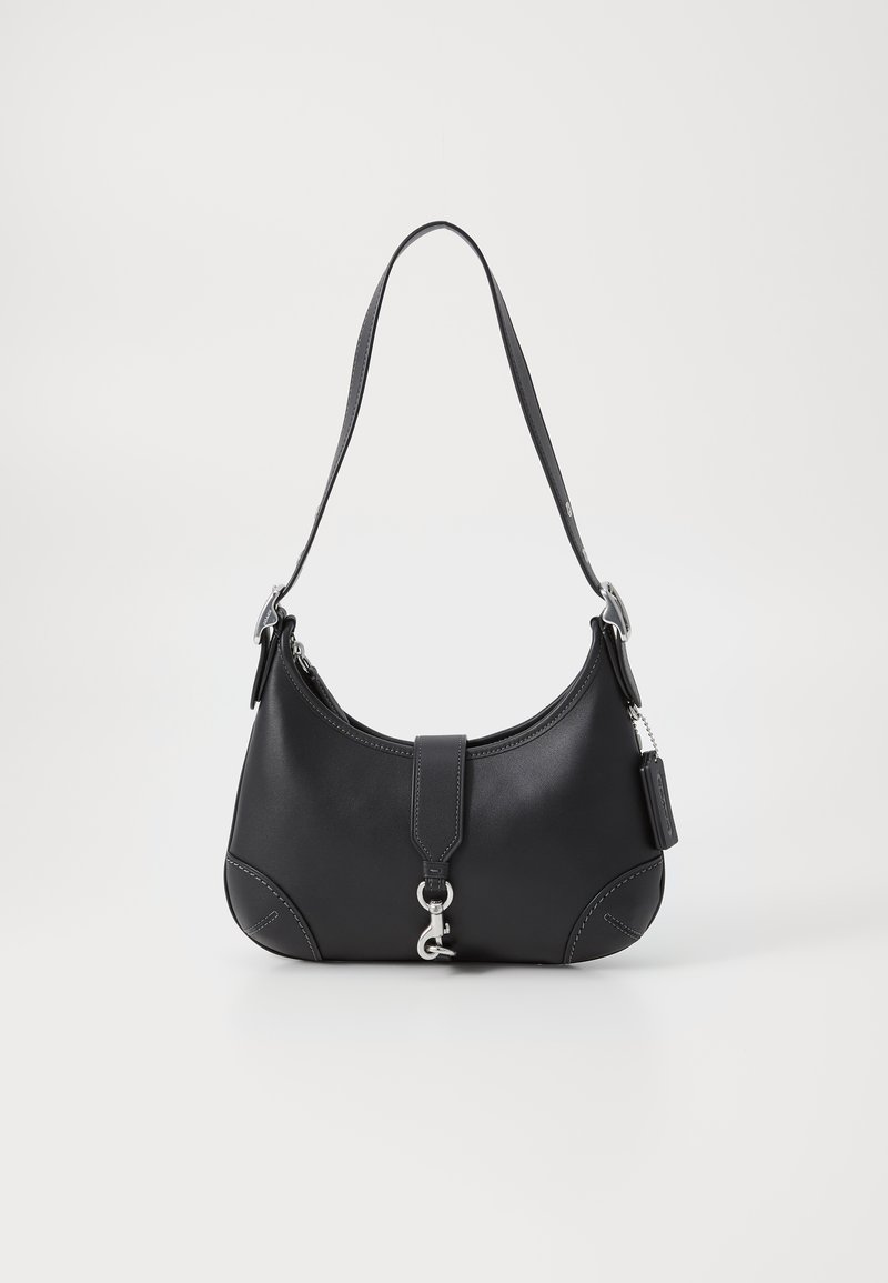 Bolsa de mão em couro preto com um formato curvo, alça superior, ferragens prateadas e costura em contraste. Apresenta uma alça frontal e detalhes em costura.