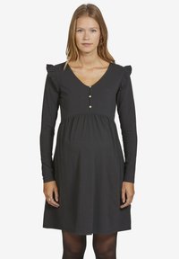 Schwarzes langärmliges Kleid mit V-Ausschnitt, Rüschendetails an den Schultern, Knopfdetails an der Vorderseite und einer lockeren Passform für eine schwangere Silhouette.