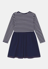 Nattblå långärmad klänning med vita horisontella ränder upptill och en enfärgad kjol, med ett sammanstramat midja och rundad halsringning.