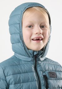 Ljusblå, kviltad pufferjacka med huva, som har en framzip och svart detaljer, samt en liten logotyp på bröstet.