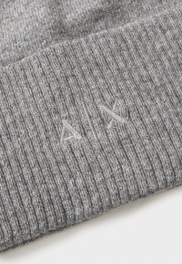Grå strikket lue med ribbestruktur. Har en subtil logo i lysere tråd på kanten. Materialet virker mykt og elastisk.