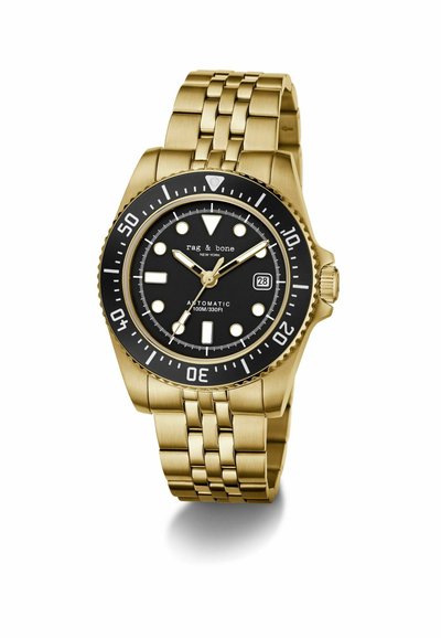 Montre-bracelet en métal doré avec cadran noir, index blancs, lunette tournante et affichage de la date indiquant le 28, de la marque « rag & bone ».