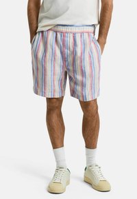 Gestreifte Shorts aus leichtem Material mit blauen, roten und gelben Linien; elastischer Bund; seitliche Taschen; kombiniert mit weißen Sneakern und Socken.