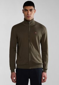 Sudadera verde oliva con cremallera, con un cuello y puños acanalados, presenta un pequeño logotipo bordado en el lado izquierdo del pecho y una textura de tela suave.