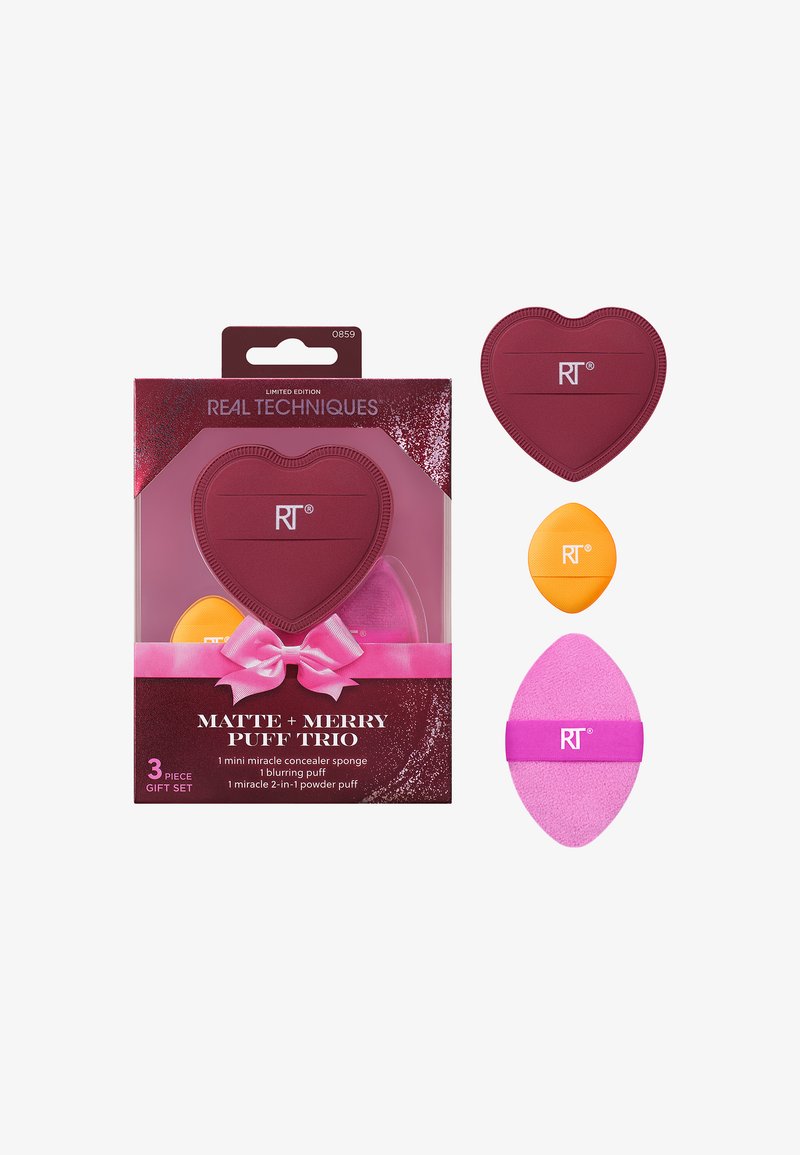 Tre spugnette per trucco: una spugna a forma di cuore di colore rosso intenso, una spugna rotonda arancione e una spugna ovale rosa con una banda viola, confezionate in una scatola colorata.