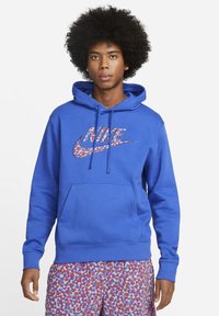 Blå hættetrøje med et stort flerfarvet Nike-logo på forsiden, der har en kængurulomme og snor i hætten.