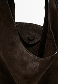 Dark brown suede bag with a flap and magnetic button closure showing close-up detail of texture and stitching.