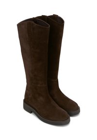 Bottes en daim marron, arrivant jusqu'au genou, avec une semelle plate, un bout arrondi et des coutures minimales. Elles sont dotées d'une sangle de traction en haut pour un enfilage facile.