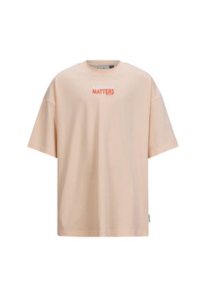 Licht perzik oversized t-shirt van zachte katoen. Heeft een ronde hals en korte mouwen met een geprinte "HAPPINESS MATTERS" ontwerp.