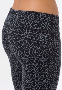 Leggings sportivi neri con un motivo geometrico grigio, caratterizzati da una vita alta e una piccola tasca con zip sul retro.