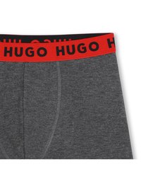 Σκούρα γκρι ανδρικά μποξεράκια με κόκκινη μέση που φέρει τη λέξη «HUGO» με έντονα μαύρα γράμματα, ορατή λεπτομέρεια ραφής μπροστά.