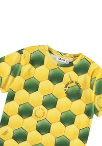 Żółta i zielona koszula z krótkim rękawem w wzór heksagonów, wykonana z lekkiego materiału. Posiada nadrukowany tekst na wzorze oraz okrągły dekolt.