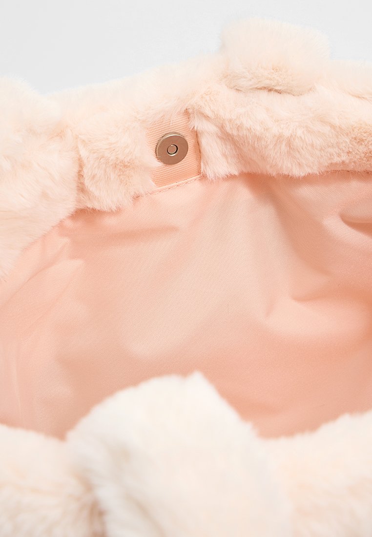 L'interno in morbido pelo sintetico rosa di una borsa presenta una fodera in raso liscio e un chiusura con bottone a pressione marrone su un lato.