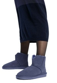Botas de tobillo de ante azul marino con una textura suave, punta redondeada y un forro de borreguillo expuesto en la parte superior. Incluye un diseño de costura simple.