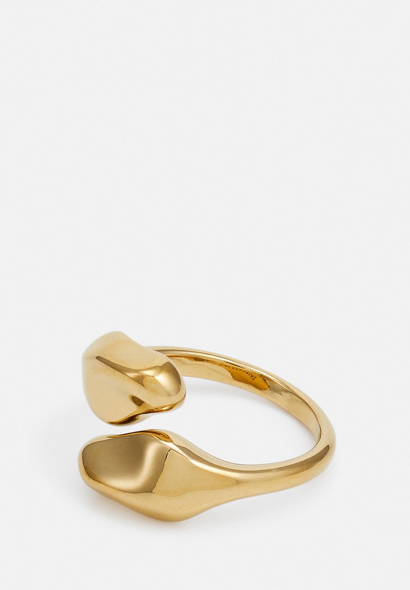 Guldtonet metalring med et abstrakt design, der har to glatte, afrundede ender, som taper. Overfladen er poleret for en blank finish.