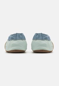Lærerslipper med en lys blå overdel og en myk beige såle, med en samlet tekstur ved ankelen og en glatt finish.
