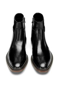 Botas de cuero negras hasta el tobillo con un acabado suave, cremalleras laterales, puntas afiladas y una suela de goma marrón contrastante.