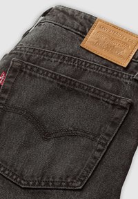 Sötétszürke farmernadrág, bőr övcsíkkal, márkás felirattal, hátsó zseb különleges varrással és piros logó címkével.