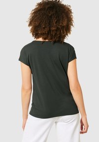 Camiseta de manga corta verde oscuro con un corte relajado, cuello redondo y textura suave. La parte posterior cuenta con un sutil diseño de dobladillo curvado.