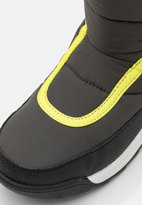 Czarny ocieplany but z wyściółką, z jasnoskalnym akcentem w okolicy kostki i teksturowaną czarną podeszwą.