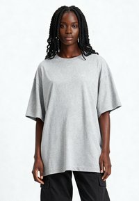 Szary, oversize t-shirt z mieszanki bawełny, krótki rękaw, okrągły dekolt i luźny fason. Noszony z czarnymi spodniami cargo. Teksturowana, gładka powierzchnia.