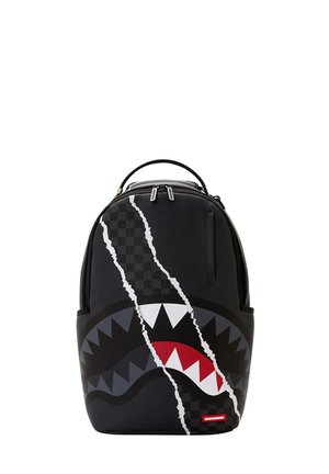 Mochila negra con un patrón a cuadros rasgado que revela un diseño de dientes de tiburón en blanco, gris y rojo en el panel frontal.