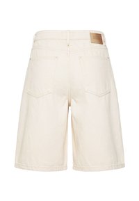 Shorts en denim écru à jambes larges, deux poches arrière, passants pour ceinture et un patch en cuir marron marqué "DRYKORN" sur la ceinture.