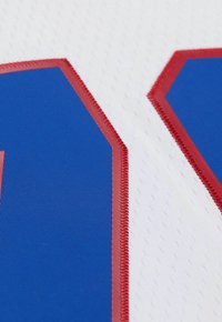 Tissu blanc avec un numéro "11" en relief de couleur bleue bordé de couture rouge, présentant un matériau lisse et brillant ainsi que des formes géométriques nettes.