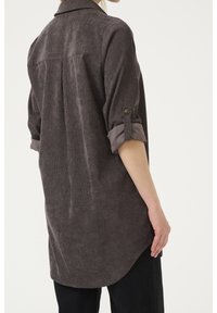 Mørkegrå langærmet skjorte i tekstureret stof med rygplissé, optrukne ærmer med knap og rundet kant.