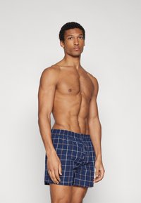 Marineblau karierte Badehose mit elastischem Bund und Karomuster in helleren Farben. Weicher Stoff mit lockerer Passform.
