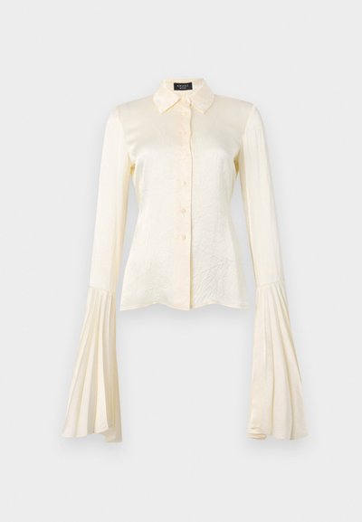 Bluză lungă cu mâneci lungi de culoare crem, cu un închidere tip buton, guler și mâneci evazate pliate. Material satinat neted cu o textură subtilă.