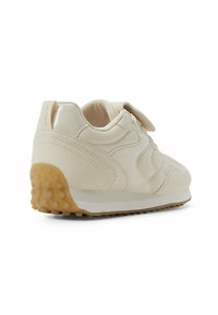 Weiße Ledersneaker mit strukturiertem Obermaterial, Klettverschluss und einer Gummisohle, die kleine Noppen für die Traktion hat. Rundliche Form und minimalistisches Design.