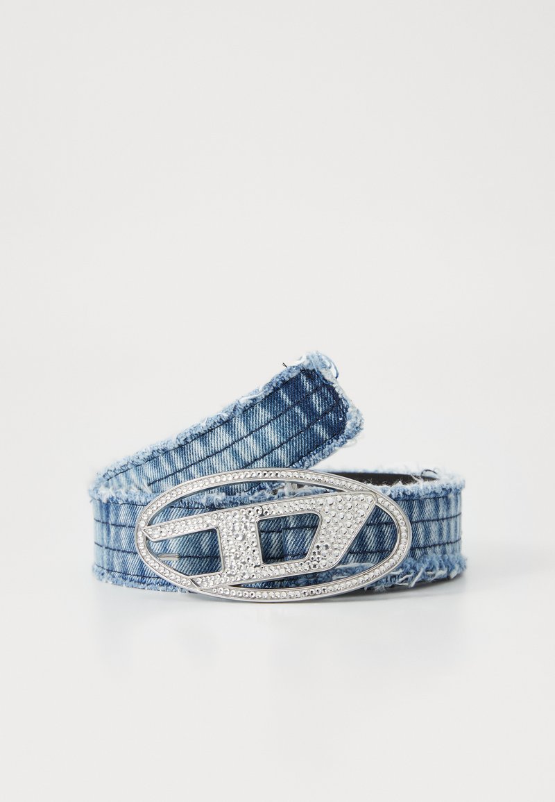 Jeansbelte med frynser, med en sølvfarget oval spenne utsmykket med klare rhinestones og et geometrisk design.